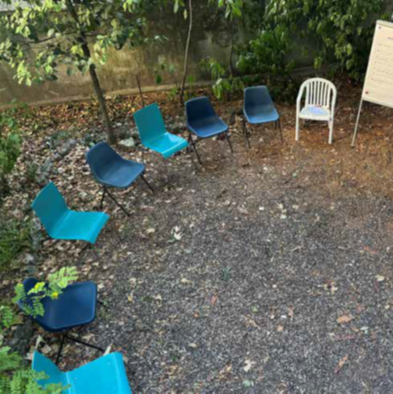 Im Garten sind St&uuml;hle in zwei verschiedenen Blaut&ouml;nen im Halbkreis aufgestellt.